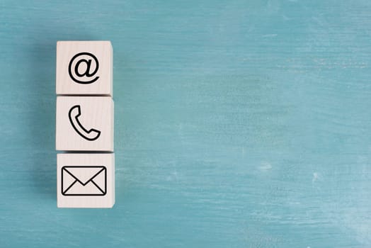 Signs for e-mail, phone and newsletter on wooden blocks, blue background