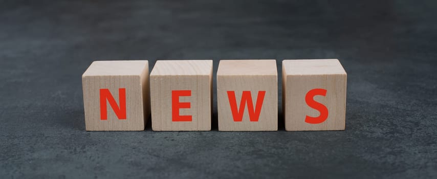 The word news is standing on wooden blocks, red color