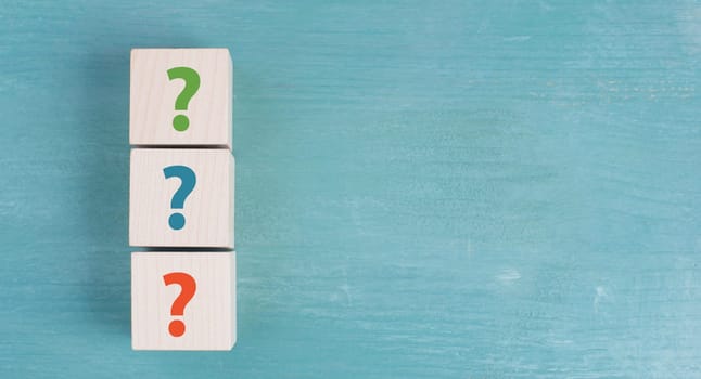 Three wooden cubes with question marks in red, blue and green color