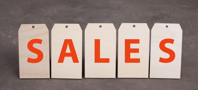 Tags with the word sales in red color, dark textured background, empty copy space