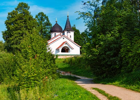 White russian church in summer with cloudy sky in background and road in foreground