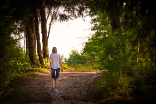 Young woman walking in summer forest in Russia.