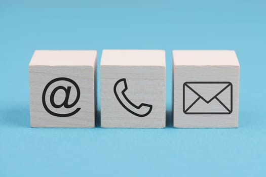 Signs for e-mail, phone and newsletter on wooden blocks, blue background, symbols and signs