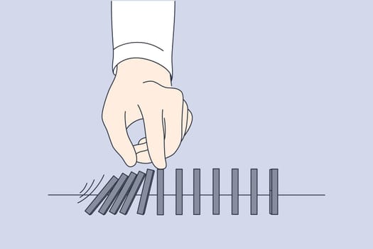 Business, game, finance, crisis, stop, management, leadership concept. Businessman leader hand pushing falling wooden blocks bricks placed on table. Playing domino stopping financial crisis banruptcy.