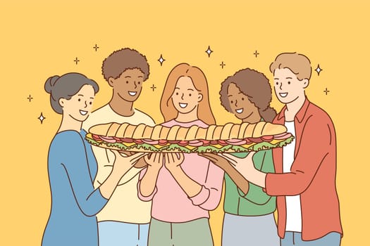 Food, friendship, togetherness, happiness, hunger concept. Group of young international multiethnic friends african american women men sharing large sandwich together. Meal for breakfast lunch dinner.