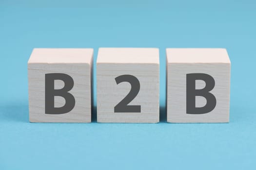 The word B2B is standing on wooden cubes, blue colored background