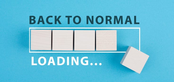 Back to normal is standing on a blue background, loading bar with wooden cubes, life after covid-19