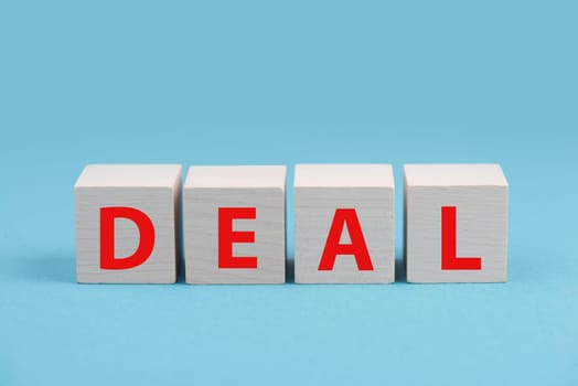 The word deal is standing in red letters on wooden cubes, blue background