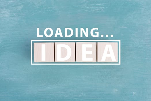 The word idea is standing on wooden cubs in white color, blue background, loading symbol