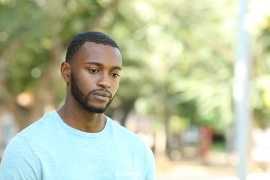 Sad black man looking away in a park