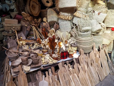 Wooden handmade bowls, spoons, boards, kitchen utensils and baskets on display at street market.