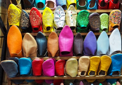 Handmade colourful leather slippers on display at traditional souk - street market in Morocco.
