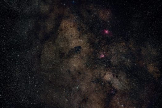 Night summer sky with milky way near Scutum constellation, bright Sagittarius clouds, purple Eagle and Swan nebula visible. Long exposure stacked photo.