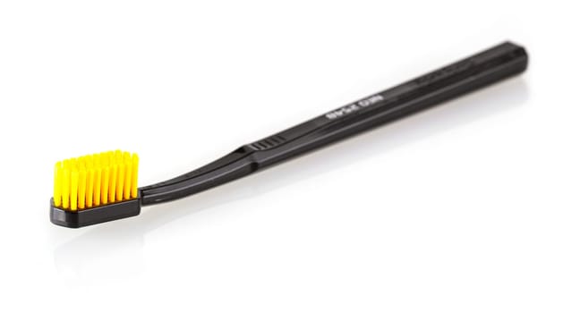 The black toothbrush with yellow bristles  isolated on white