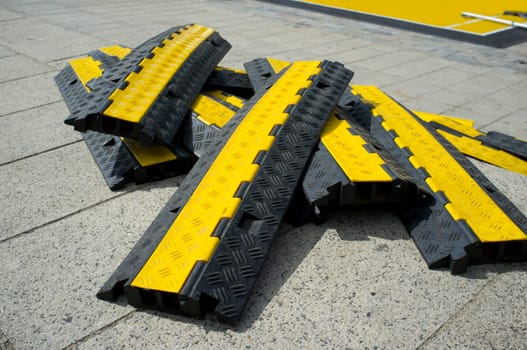Rubber two channel protector ramp pilled up over urban historic quarter granite floor. Heavy duty cable protectors next to event site