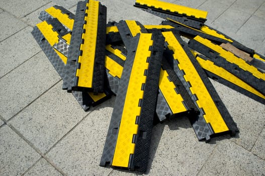 Rubber two channel protector ramp pilled up over urban historic quarter granite floor. Heavy duty cable protectors next to event site