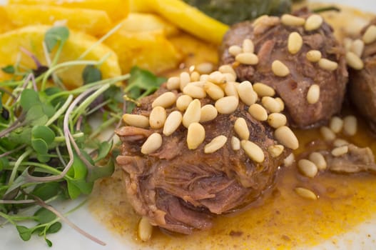 Stew cheek pieces of iberian topped with pine nuts and corn salad. Closeup