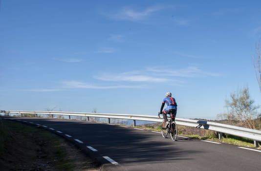 Mature biker ascending mountain pass. Road biking by Extremadura , Spain