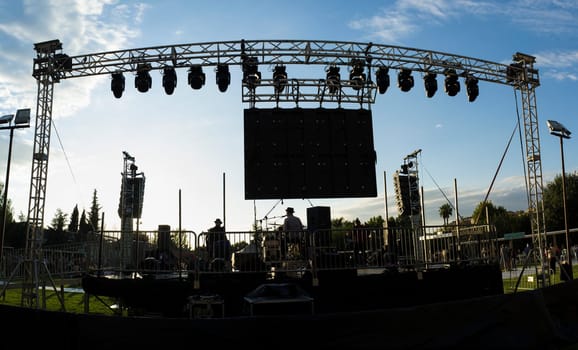 Rock daylight performance seen from rear stage. Sunset blue sky background