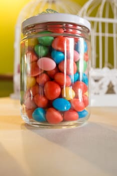 Colorful candied sweets pebbels, displayed in glass jar. Selective focus