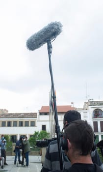 Sound technician with shotgun microphone covers a politician appearance. Local government press issues
