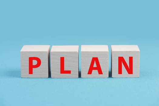 The word plan is standing on wooden cubes in red color, blue background