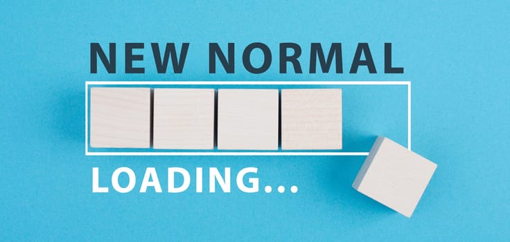 The words new normal are standing on wooden cubes, loading bar, blue colored background