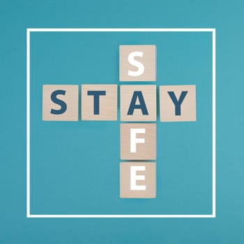The words stay safe are standing on wooden cubes, blue background, Covid-19
