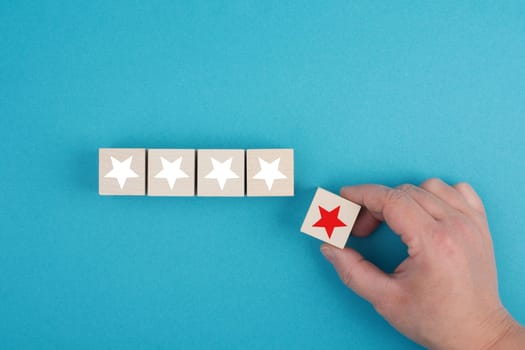 Wooden cubes with white stars, one block with a red star holding in the hand