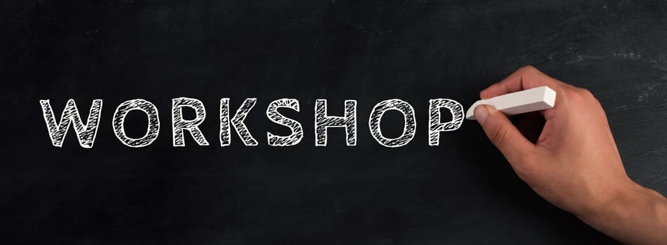 The word workshop is written on a chalkboard,hand with with chalk