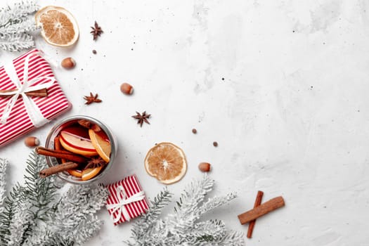 Christmas flat lay top view on white gray concrete background table with Mulled Wine glass cup or mug, present red gift boxes, decorations, cinnamon, orange slices, spices, fir. Christmas time photo