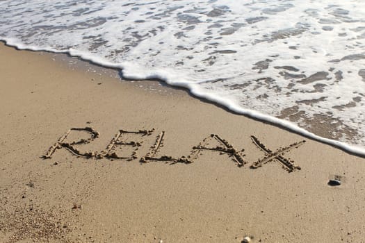 Relax word written in the sand