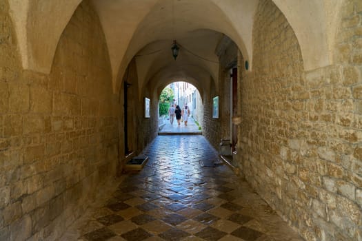 Tourists at a passage at the Cathedral of St. Quirinus in the old town of Krk in Croatia