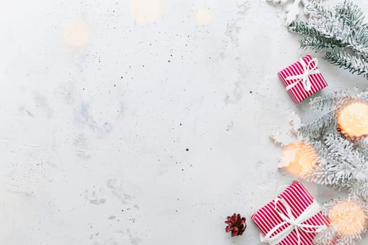 Christmas, New Year gray concrete flat lay. Red white striped present gift boxes top view. Gift ribbon and packaging paper. Christmas tree fir, cones, toy balls, wooden star. Copy space area on photo