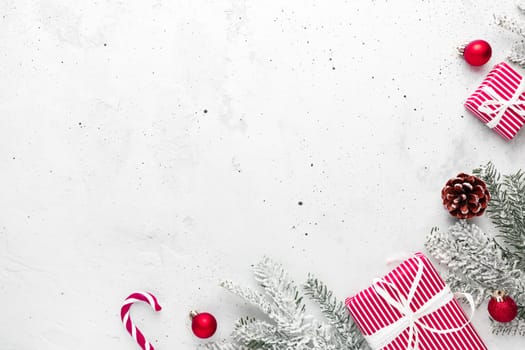Christmas, New Year gray concrete flat lay with red white present gift boxes top view. Gift ribbon and packaging paper. Christmas tree fir, cones, toys, candy stick lolly, Copy space text area