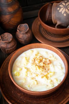 Milk soup on wooden table with pottery tableware, vertical image
