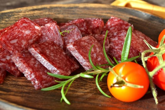 Russian cuisine: dry sausage, sliced salami on wooden board closeup