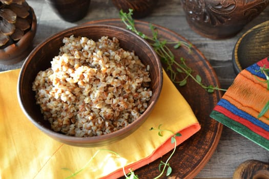 Cooked buckwheat porridge in a deep bowl on a wooden background
