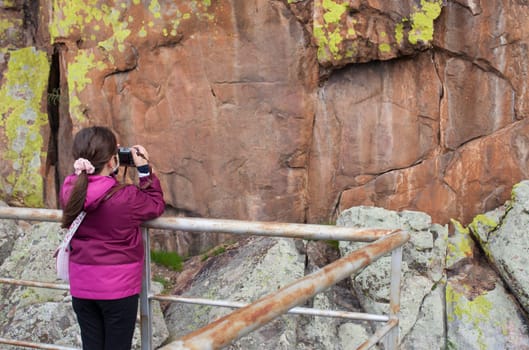 Little girl taking pictures to San Blas rock shelter with prehistorical paintings. Alburquerque, Badajoz, Extremadura, Spain