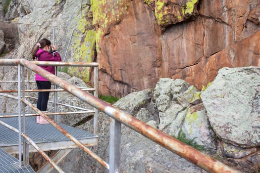 Little girl taking pictures to San Blas rock shelter with prehistorical paintings. Alburquerque, Badajoz, Extremadura, Spain