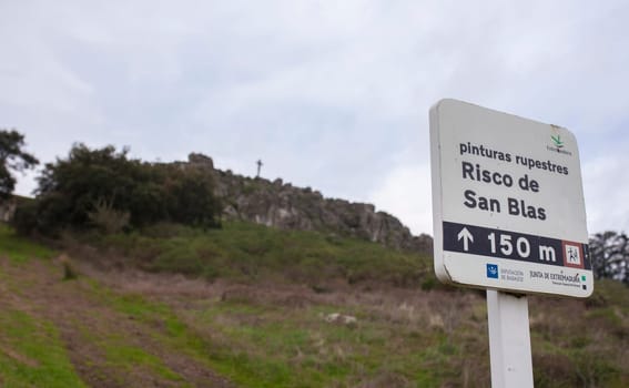 Alburquerque, Spain - Feb 21st, 2021: San Blas rock shelter information pole pointing to prehistorical paintings. Alburquerque, Badajoz, Extremadura, Spain