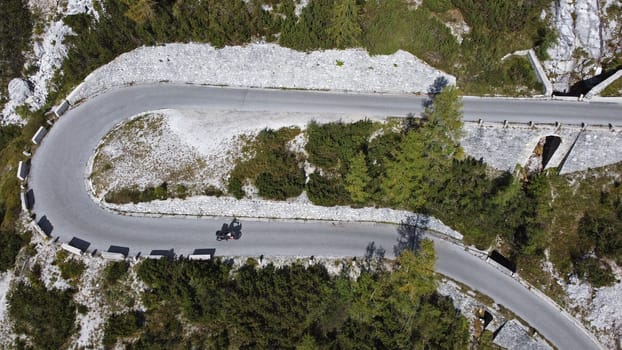 Aerial drone shot of motorcyclist on winding mountain road