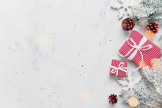 Christmas, New Year gray concrete flat lay. Red white striped present gift boxes top view. Gift ribbon and packaging paper. Christmas tree fir, cones, toy balls, wooden star. Copy space area on photo