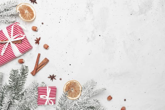 Christmas flat lay top view on white gray concrete background table with present red gift boxes, decorations, cinnamon sticks, hazelnut, dried orange slices, various spices, fir, anise, aniseed