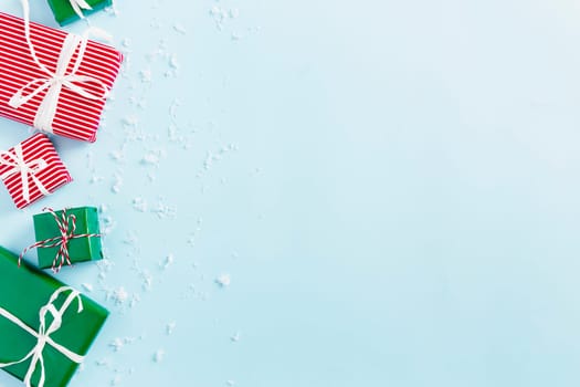 Christmas and New Year blue flat lay with various red, white and green present gift boxes top view. Gift ribbon and packaging paper. Decorating snow flakes. Copy space text area. High quality photo