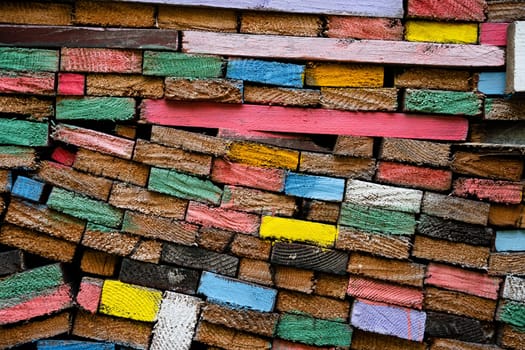 closeup front view of stacked wooden planks decorated with paint in different colors