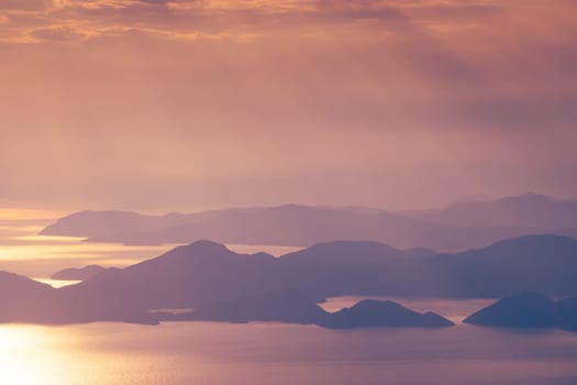beautiful aerial panorama from the Babadag peak of high mountains rising up over the Mediterranean sea at sunset near Oludeniz Blue Lagoon coast in Turkey during summer