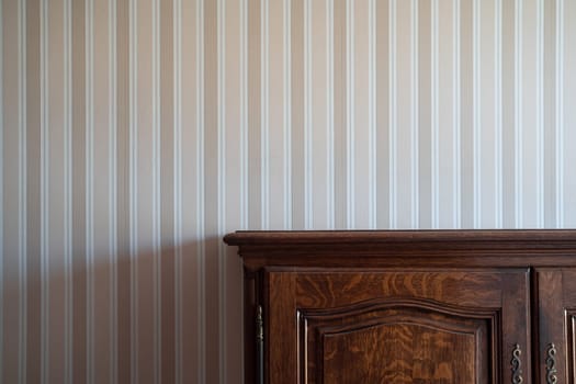 front view close up of empty brown vintage drawer wooden cabinet against a white wall with beige stripes