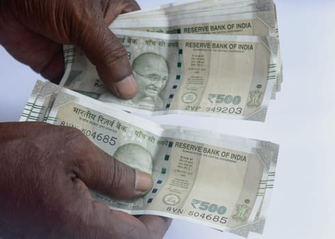 Senior aged Man hand counting Indian rupee note on table. High angle view. Close up.