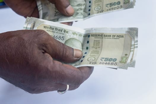 Senior aged Man hand counting Indian rupee note on table. High angle view. Close up.